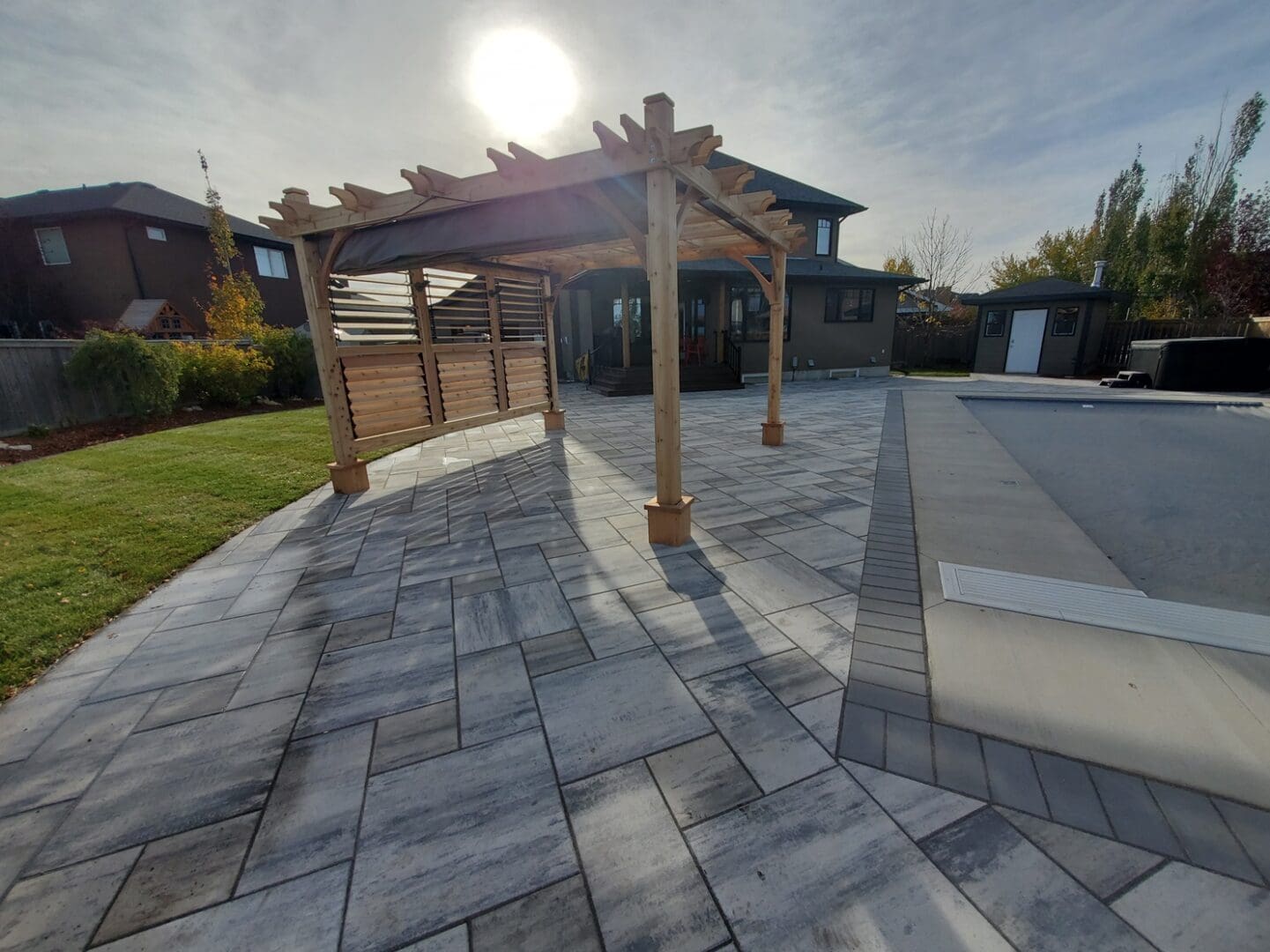 A large patio with a wooden pergola and stone steps.